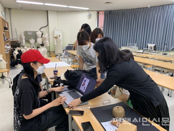 평택대 빈 강의실에서 제품 제작 회의를 열어 학과 교수에게 포스터를 확인 받는 모습