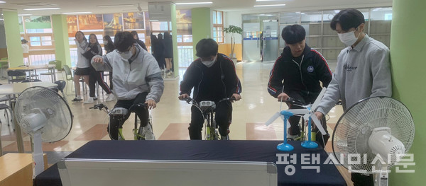 비전고 에코존에서 학생들이 전기를 생산하기 위해 전기 발전 체험 자전거의 페달을 열심히 밟고 있다.