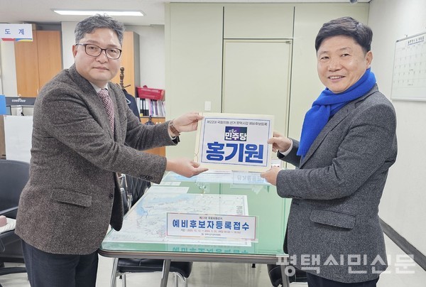 1월 29일 평택시선거관리위원회에서 홍기원 국회의원(오른쪽)이 선관위 관계자에게 예비후보 등록 서류를 전달하고 있다. 