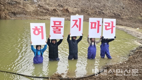 경기남부하천유역네트워크 회원들이 15일 청북읍 백봉교 아래에서 물속에 들어가 방제둑을 ‘허물지 말라’는 펼침막 시위를 하고 있다.