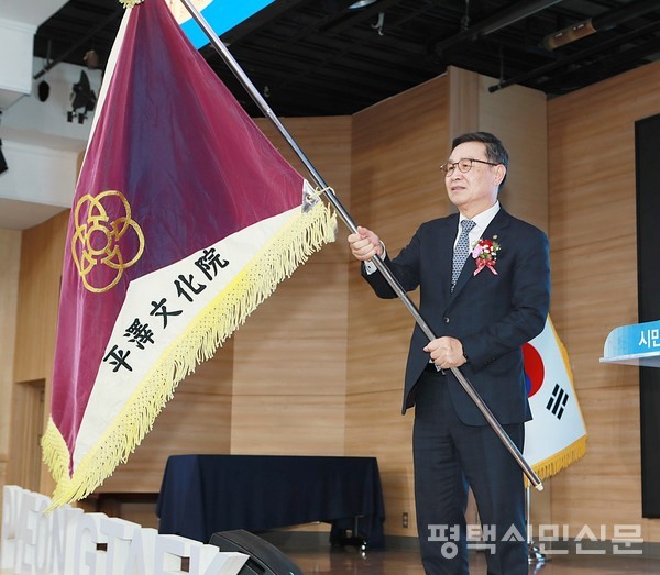 제15대 평택문화원장으로 취임한 오중근 신임 원장이 이보선 전임 회장으로부터 전달받은 문화원기를 흔들고 있다.