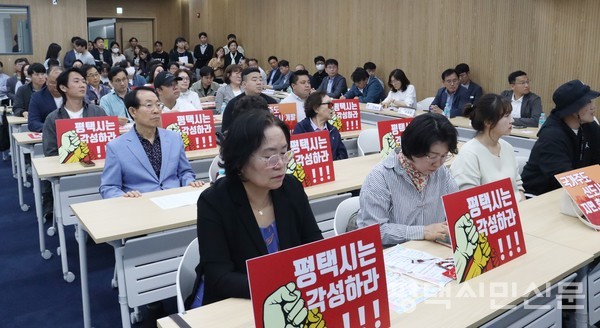 5월 10일 평택상공회의소 컨퍼런스룸에서 개최된 ‘고덕국제화계획지구 현안사업 설명회’에 참석한 고덕국제화지구 주민들이 ‘평택시는 각성하라’ 등의 문구가 적힌 피켓을 앞에 놓은 채 설명을 듣고 있다.