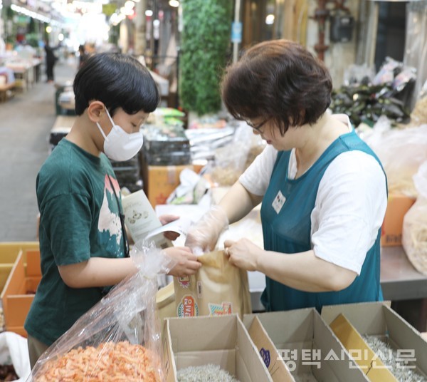 송북초 학생이 송탄시장에 있는 건어물 가게에서 마른 멸치를 사며 장보기 체험을 하고 있다. 