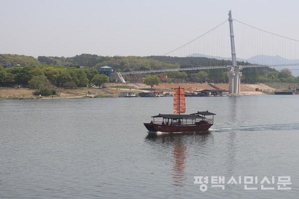 남한강 유람선 황포돛배가 상춘객을 태우고 출렁다리 아래로 운항 중이다.