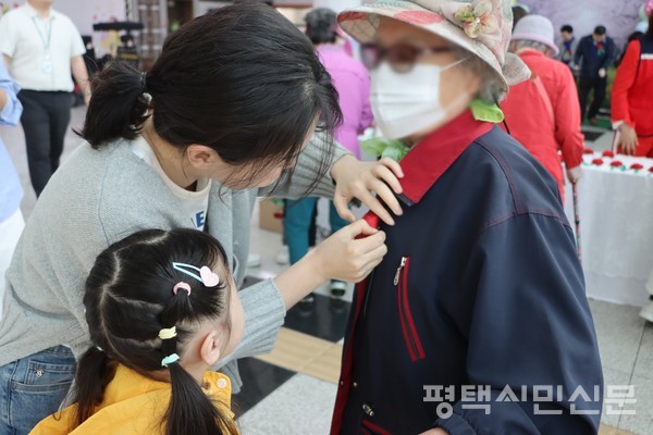 어버이날을 맞아 평택북부노인복지관에서 한스유치원 원아와 학부모가 카네이션을 달아주고 있다.